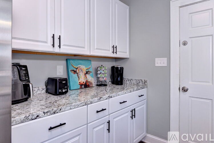 A kitchen with white cabinets and a marble countertop.