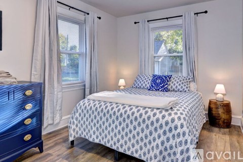 A bedroom with a blue and white bedspread and a wooden dresser.
