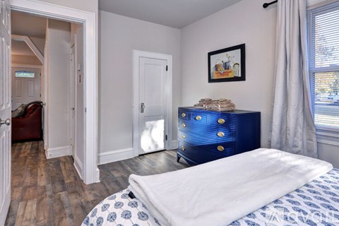 A bedroom with a blue and white bedspread and a blue chest of drawers.