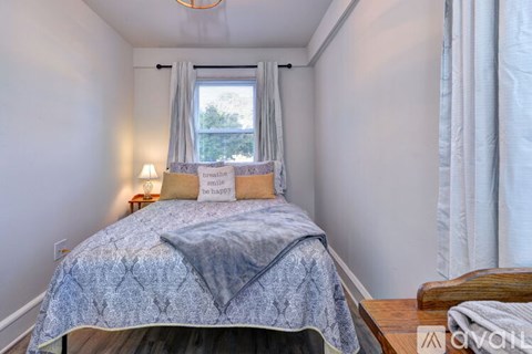 A bedroom with a bed, a window with curtains, and a lamp on a nightstand.