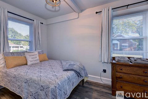 A bedroom with a bed, dresser, and window with blinds.