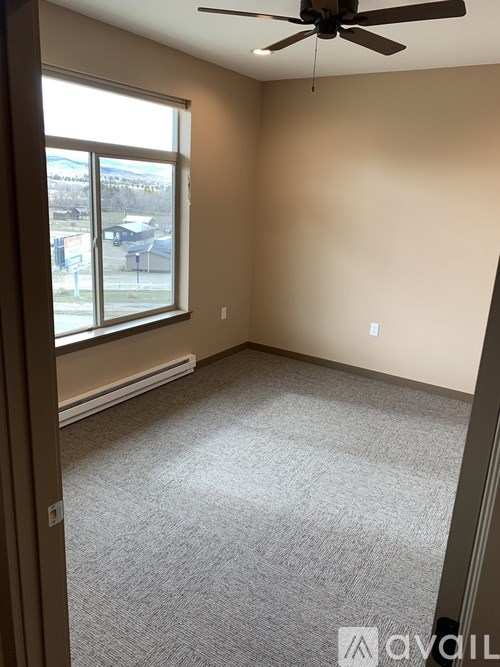 A room with a carpeted floor and a ceiling fan.