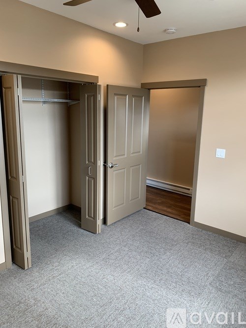 A room with a carpeted floor and two open doors.