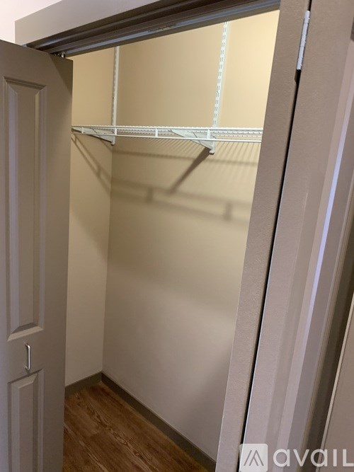 A white door is open to a room with a white wall and a wooden floor.