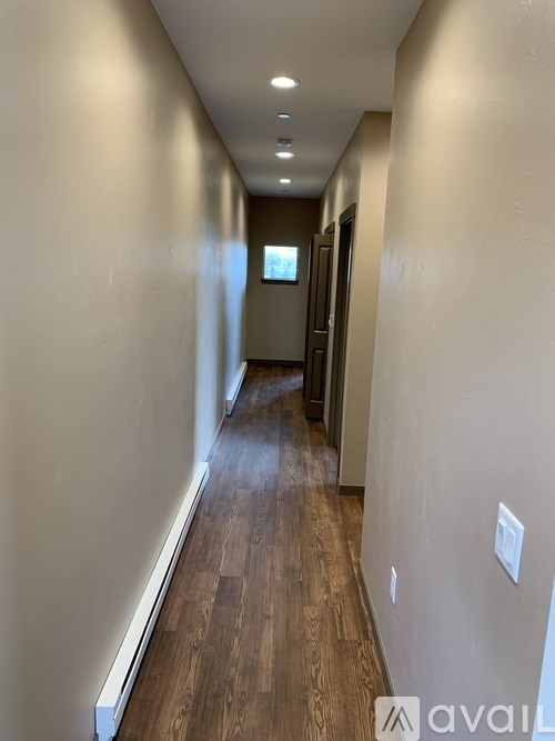 A long hallway with wood floors and white walls.
