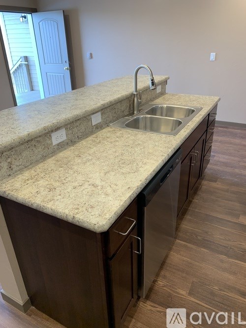 A kitchen with a granite countertop and stainless steel appliances is available for rent.