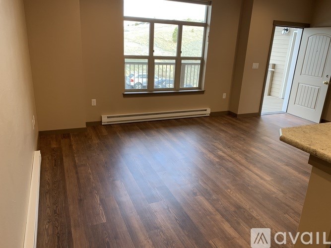 A room with wooden flooring and a window overlooking a parking lot.