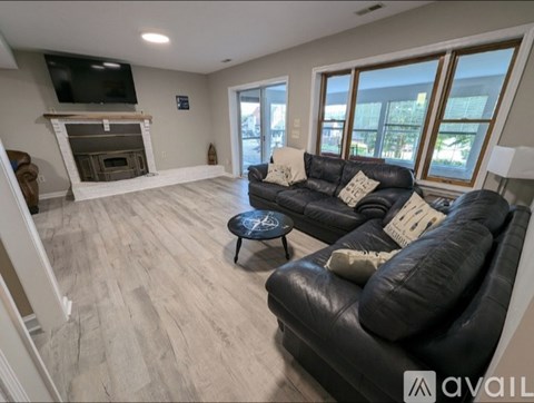 A living room with a black leather couch and a fireplace.