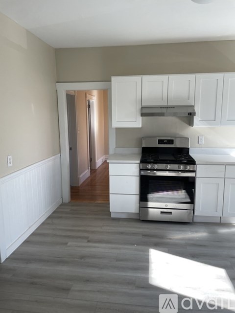 A kitchen with a stove top oven and white cabinets.