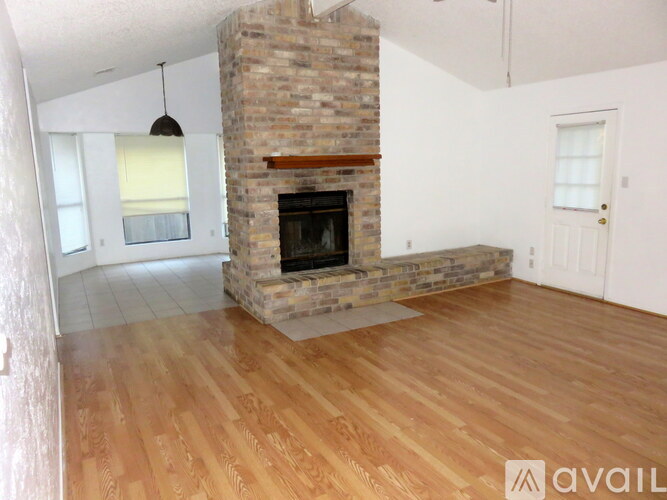 A room with a stone fireplace and wooden flooring.