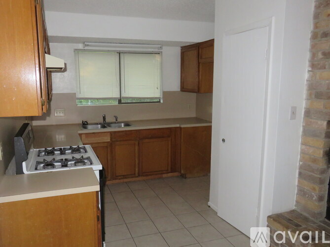 A kitchen with a stove, sink, and cabinets.