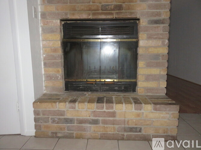 A brick fireplace with a black grate in the middle.