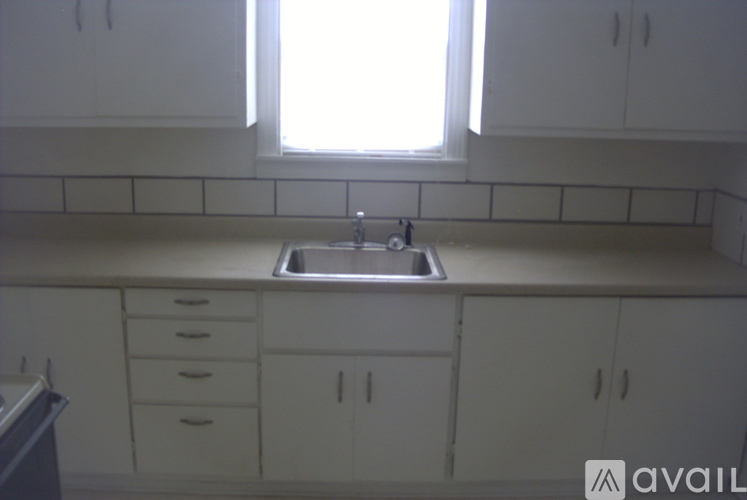 A kitchen with white cabinets and a window above the sink.