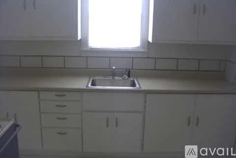 A kitchen with white cabinets and a window above the sink.