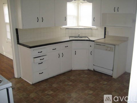 A kitchen with white cabinets and a tiled floor.