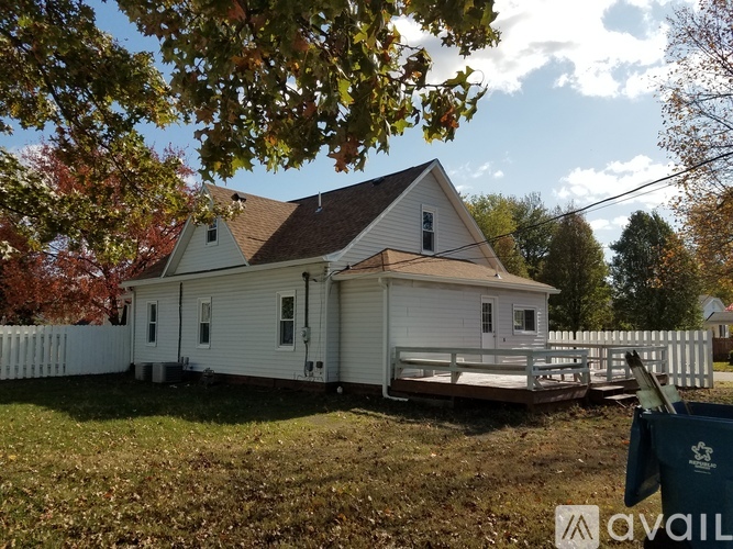 A white house with a brown roof and a fence in front of it.