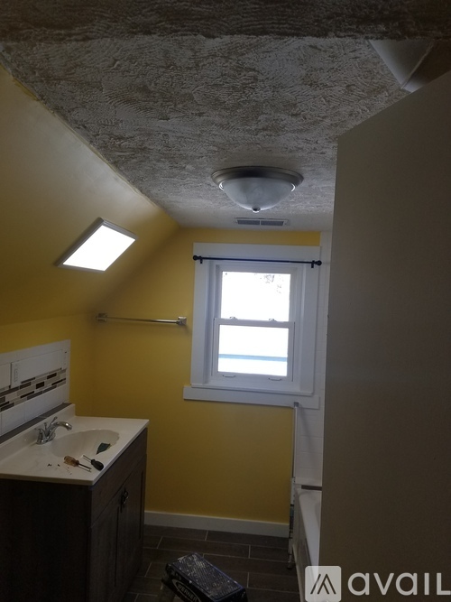 A bathroom with yellow walls and a window.