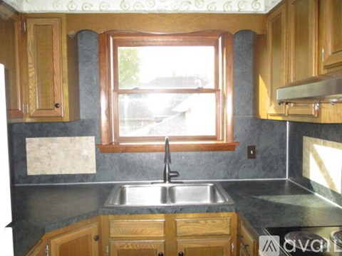 A kitchen with wooden cabinets and a window above the sink.