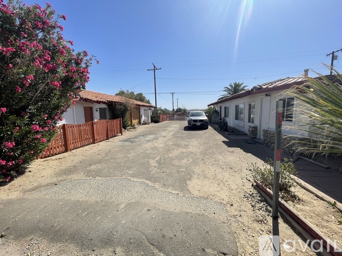 A residential street with houses on both sides and a car parked in the middle.