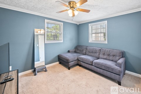 A living room with a grey couch and a ceiling fan.