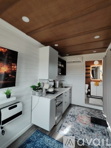 A modern kitchen with white cabinets and a wooden ceiling.