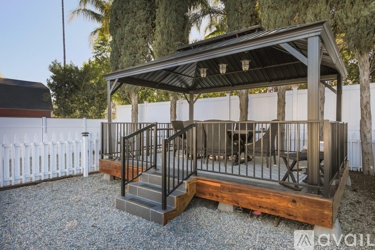 A wooden deck with a metal railing and steps leading up to a covered area.