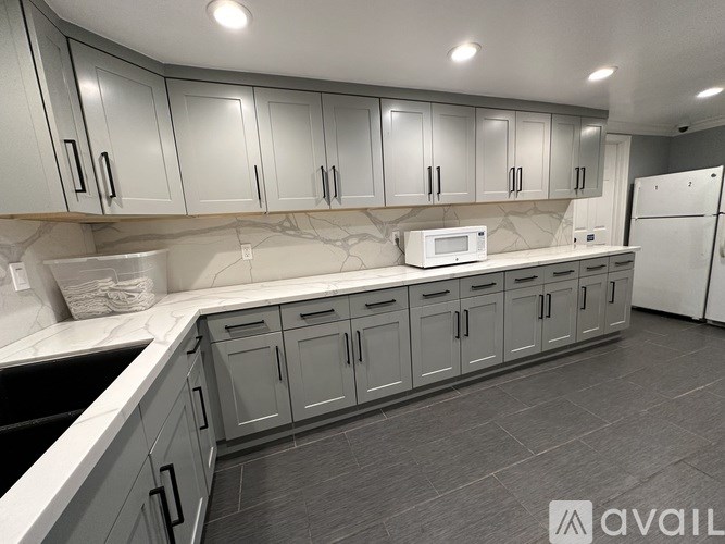 A kitchen with grey cabinets and a white fridge.