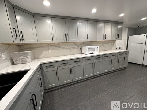 A kitchen with grey cabinets and a white fridge.