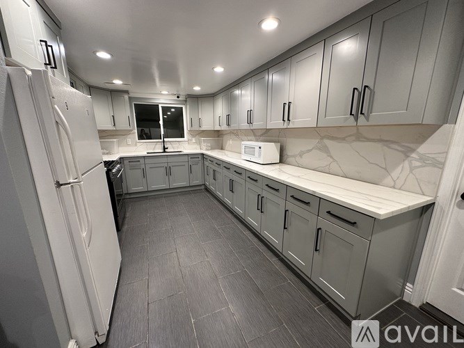 A kitchen with a white refrigerator and grey cabinets.