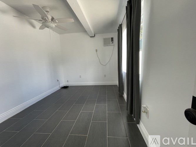 A room with a ceiling fan and sliding glass doors.