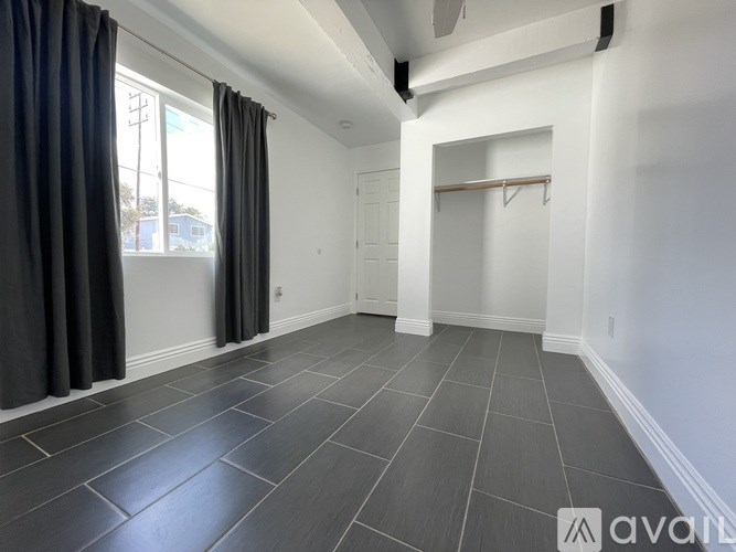 A spacious room with grey tiled flooring and white walls.