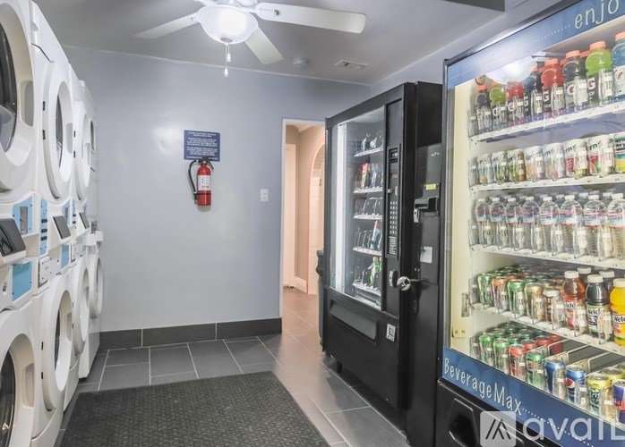 A room with a washing machine, a fridge, and a fan.