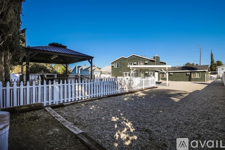 A house with a white picket fence and a gravel driveway.