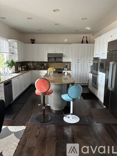 A kitchen with a table and two chairs in the middle.
