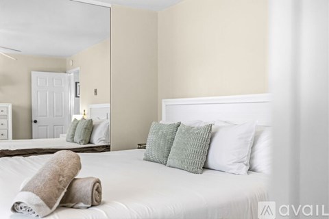 A bedroom with a white bed and a mirror on the wall.