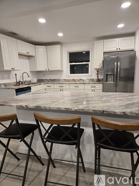 Two black chairs with wooden armrests are in front of a marble countertop.