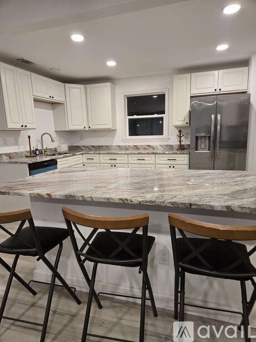 Two black chairs with wooden armrests are in front of a marble countertop.