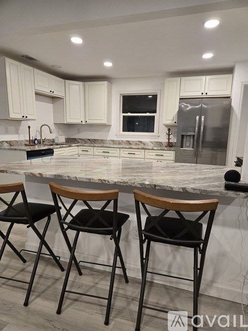 A kitchen with a marble countertop and two barstools.