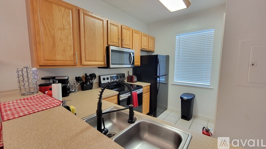 A kitchen with wooden cabinets and a black refrigerator.