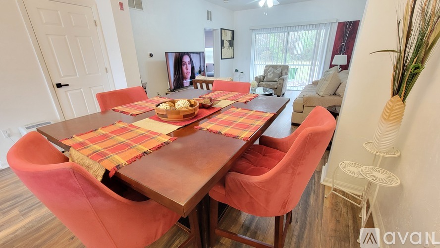 A dining room with a wooden table and red chairs.
