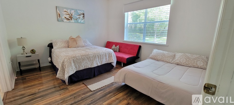 A bedroom with a large bed and a red chair.
