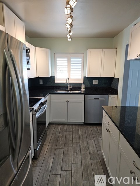 A kitchen with a stainless steel refrigerator and wooden flooring.