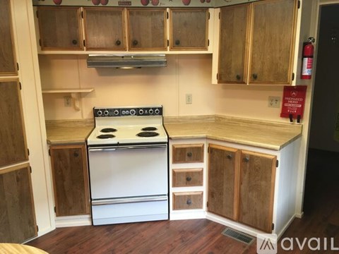 A kitchen with wooden cabinets and a white stove top oven.