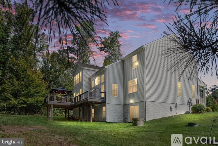 A house with a balcony and a deck is surrounded by trees.