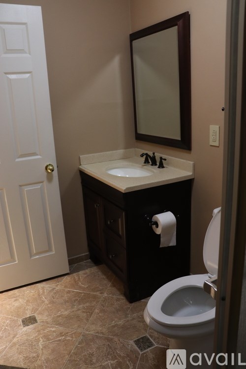 A bathroom with a toilet, sink, and mirror.