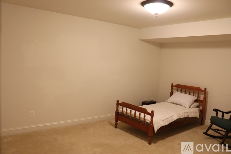 A bedroom with a bed, chair, and a ceiling light.