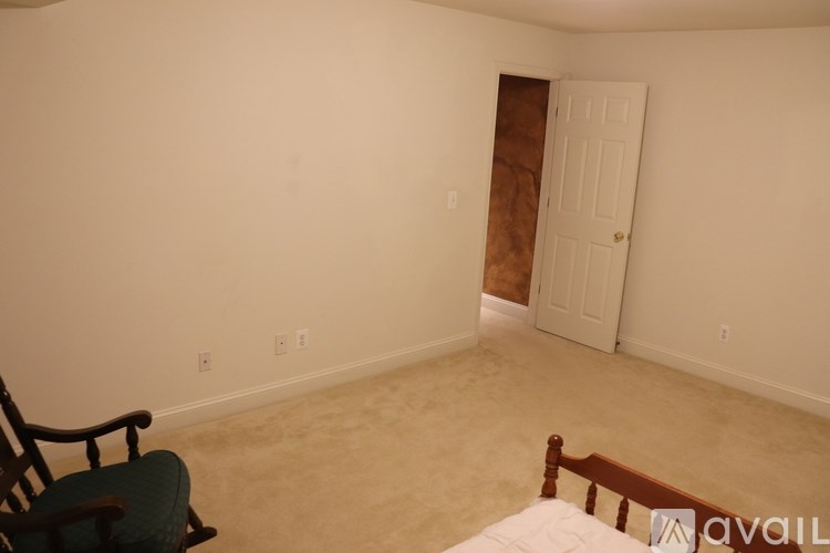 A room with a bed, a chair, and a door.