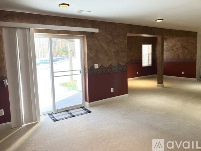 A room with a brown wall and a window with a view of a driveway.