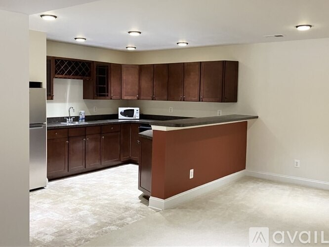 A kitchen with brown cabinets and a white microwave.
