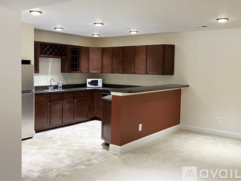 A kitchen with brown cabinets and a white microwave.
